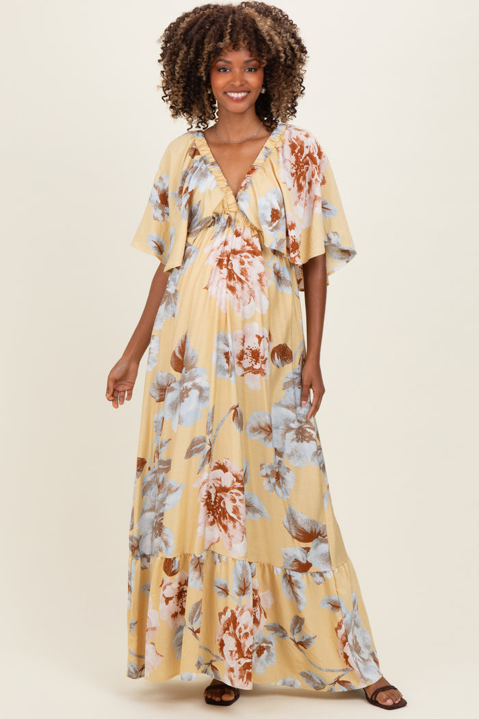 woman wearing a yellow floral maternity maxi dress with short sleeves and a V-neckline, showcasing her baby bump