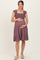 woman wearing a mauve maternity dress with ruffled sleeves and a smocked bodice, gently holding her baby bump
