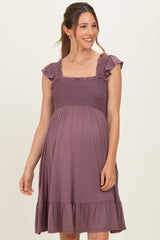 woman wearing a lavender maternity dress with ruffled sleeves and a smocked bodice, showcasing her baby bump