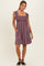 woman wearing a lavender smocked sundress with ruffled straps and pockets, standing on a light background