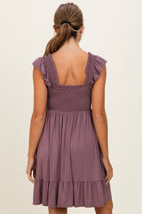 woman wearing a mauve sleeveless dress with ruffled straps and a shirred bodice, featuring a tiered skirt at the hem