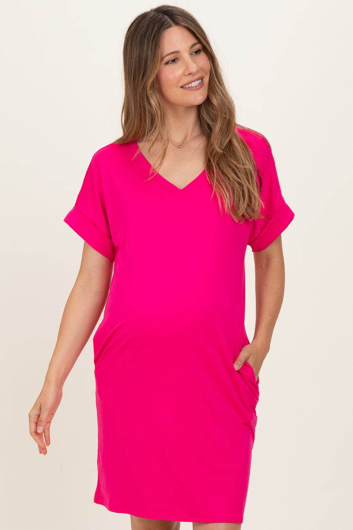 woman wearing a bright pink v-neck maternity dress with short sleeves and pockets, showcasing her baby bump