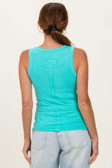 woman wearing a turquoise sleeveless ribbed top with a bow detail on the back and light blue jeans