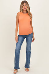 woman wearing a bright orange sleeveless maternity top showing her baby bump and paired with light blue jeans