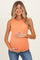 woman wearing an orange ribbed maternity tank top and holding her baby bump