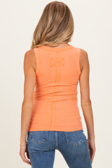 woman wearing a back view of a bright orange maternity tank top paired with blue jeans