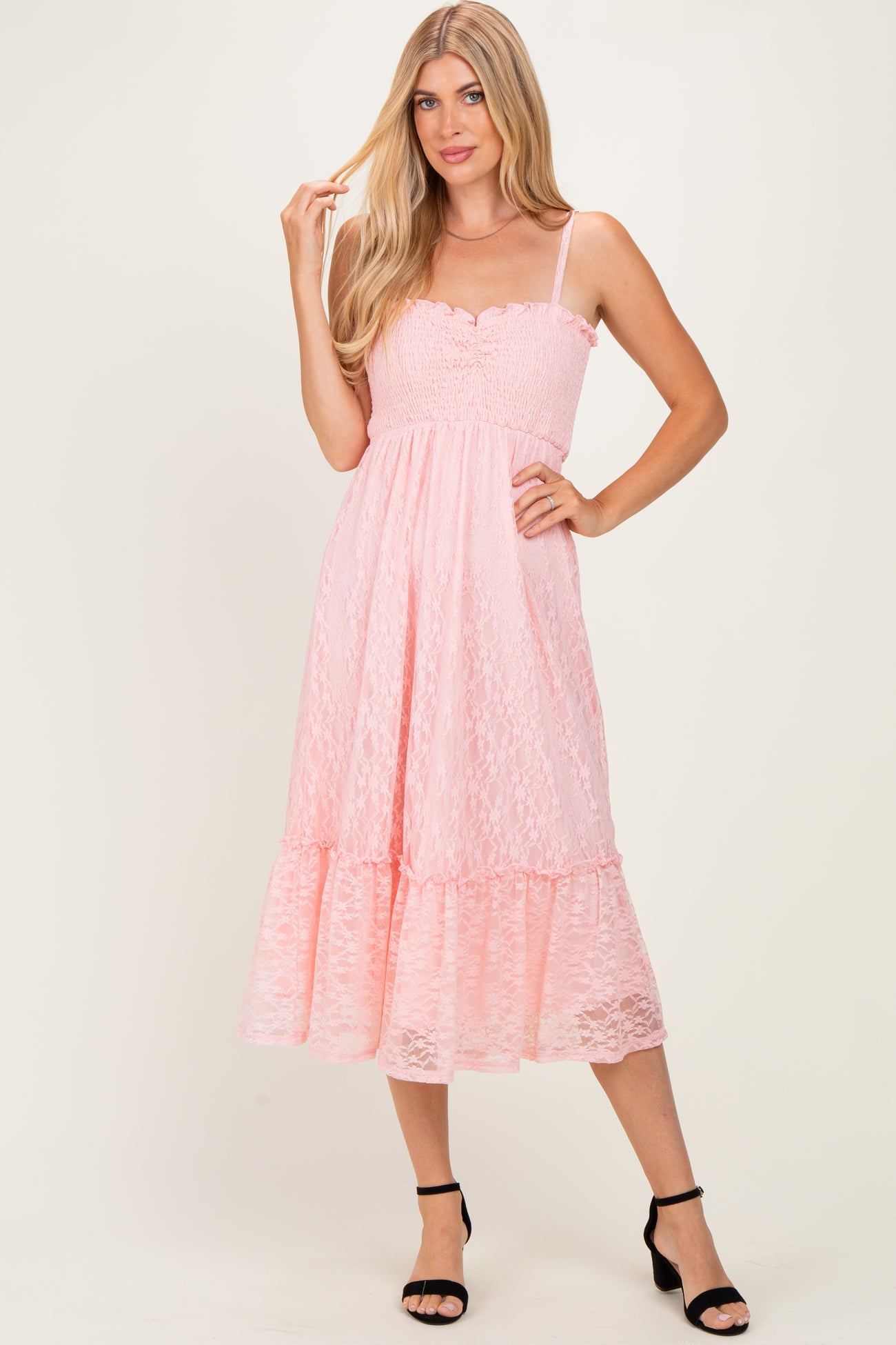 woman wearing a pink lace midi dress with spaghetti straps and a ruffled hem