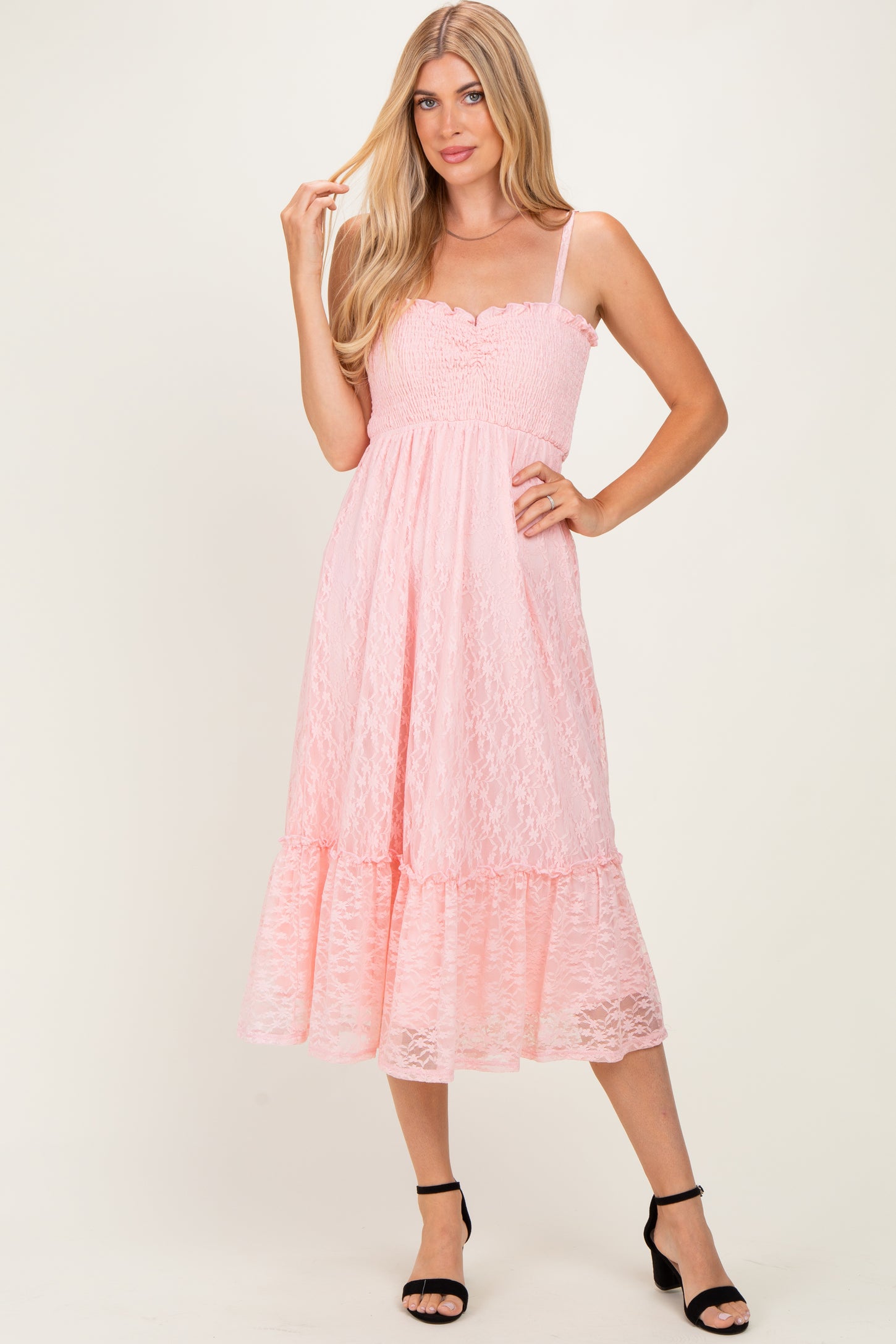 woman wearing a pink lace midi dress with spaghetti straps and a ruffled hem