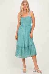 woman wearing a teal smocked midi dress with lace detailing and a ruffled hem, paired with white block heel sandals