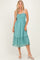 woman wearing a teal smocked midi dress with lace detailing and a ruffled hem, paired with white block heel sandals