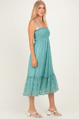 woman wearing a teal lace midi dress with spaghetti straps and a ruffled hem, standing in profile