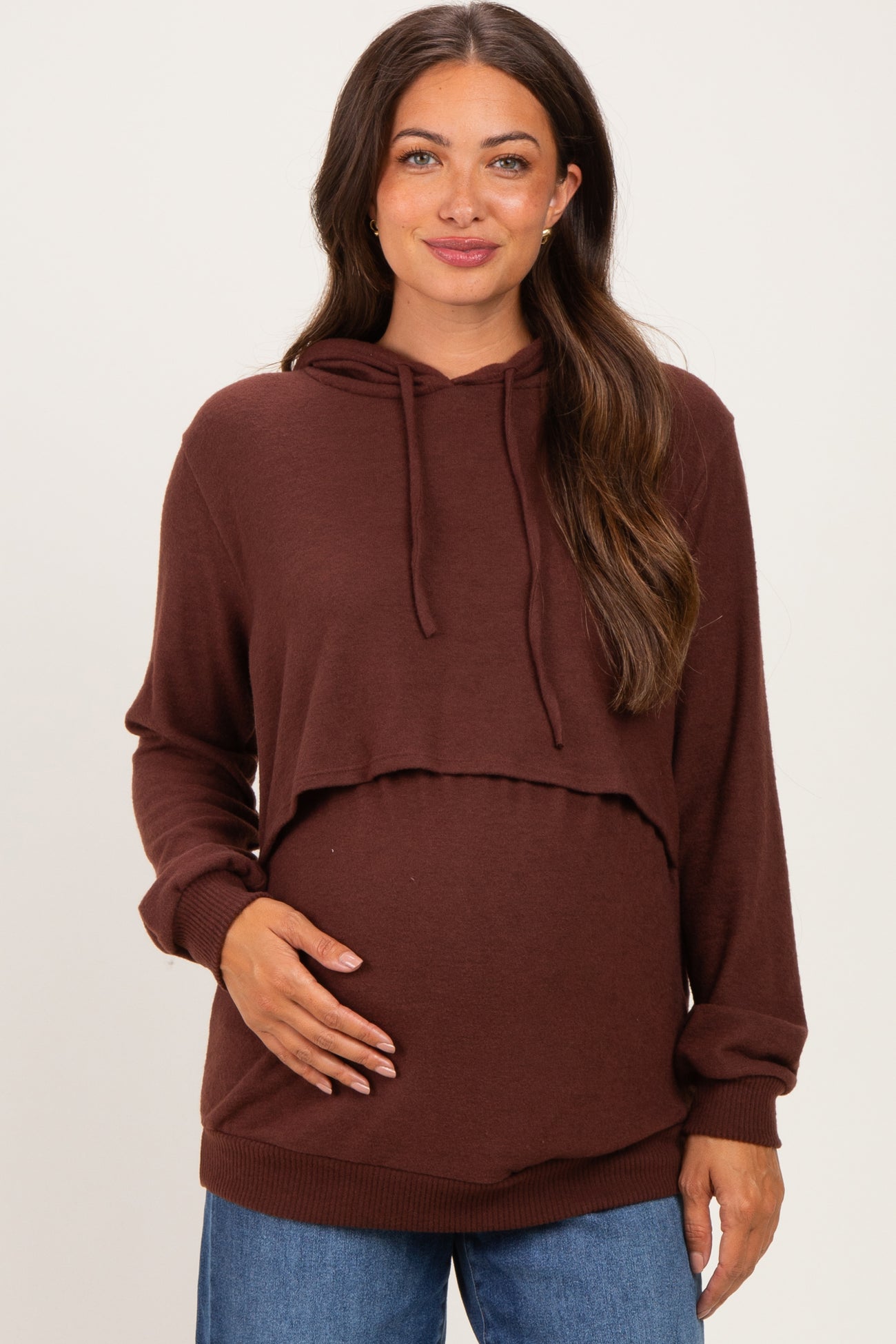 woman wearing a brown cropped hoodie maternity top and holding her baby bump