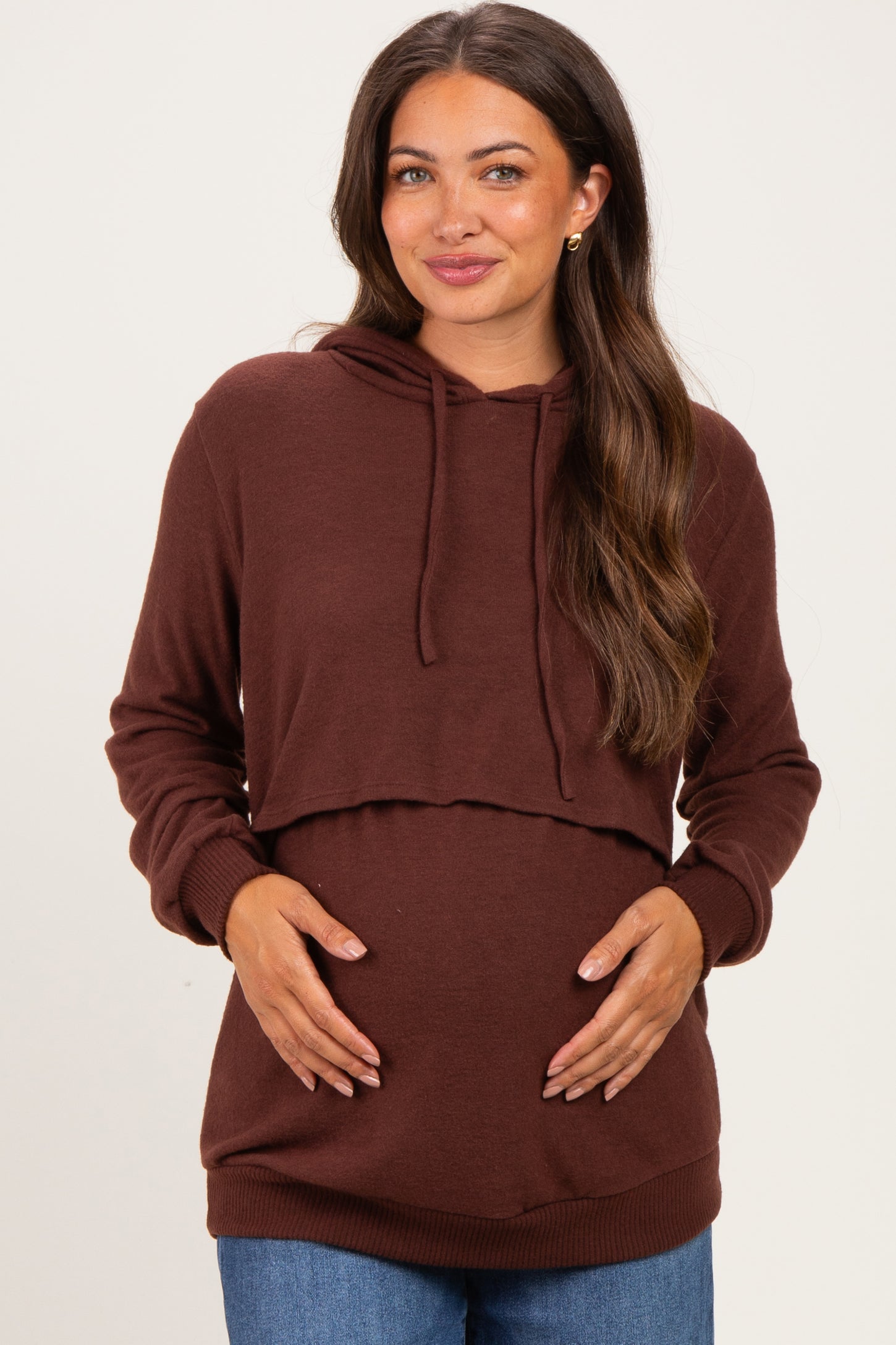 woman wearing a dark brown maternity hoodie, highlighting her baby bump with a relaxed fit and cropped style