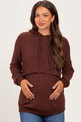 woman wearing a dark brown maternity hoodie, highlighting her baby bump with a relaxed fit and cropped style