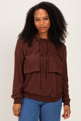 woman wearing a brown oversized hoodie with a layered design and long sleeves, paired with blue jeans