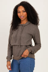 woman wearing a brown layered hoodie with a drawstring and long sleeves, paired with blue jeans