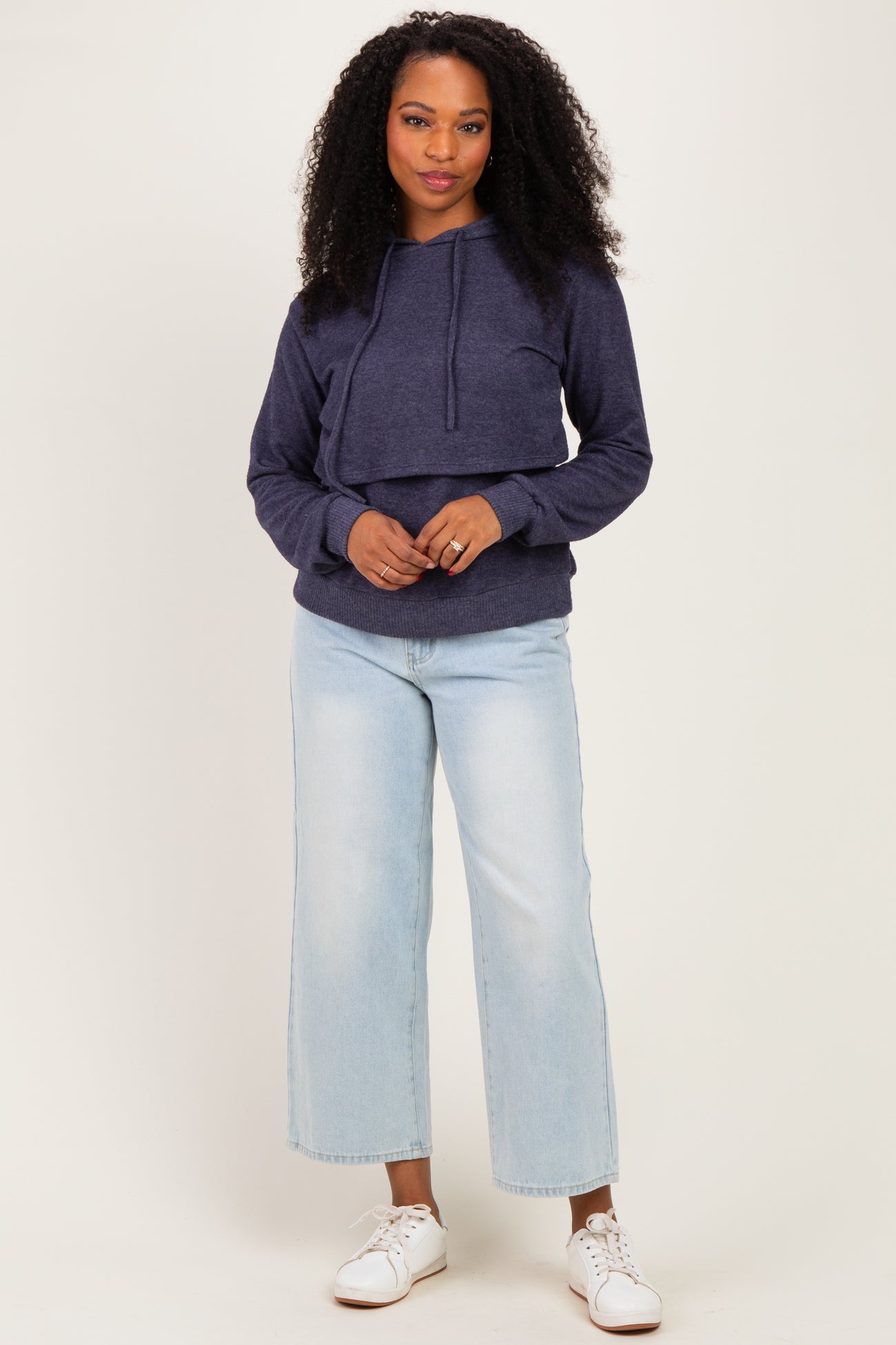 woman wearing a navy blue cropped hoodie with adjustable drawstrings and light blue wide-leg jeans