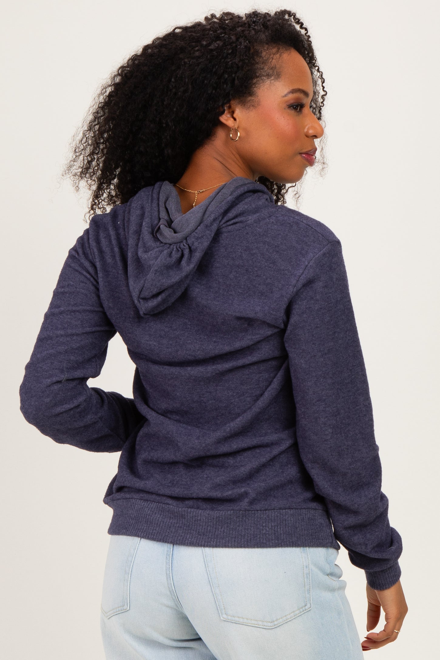 woman wearing a dark blue hoodie with a front pocket and a drawstring hood, seen from the back