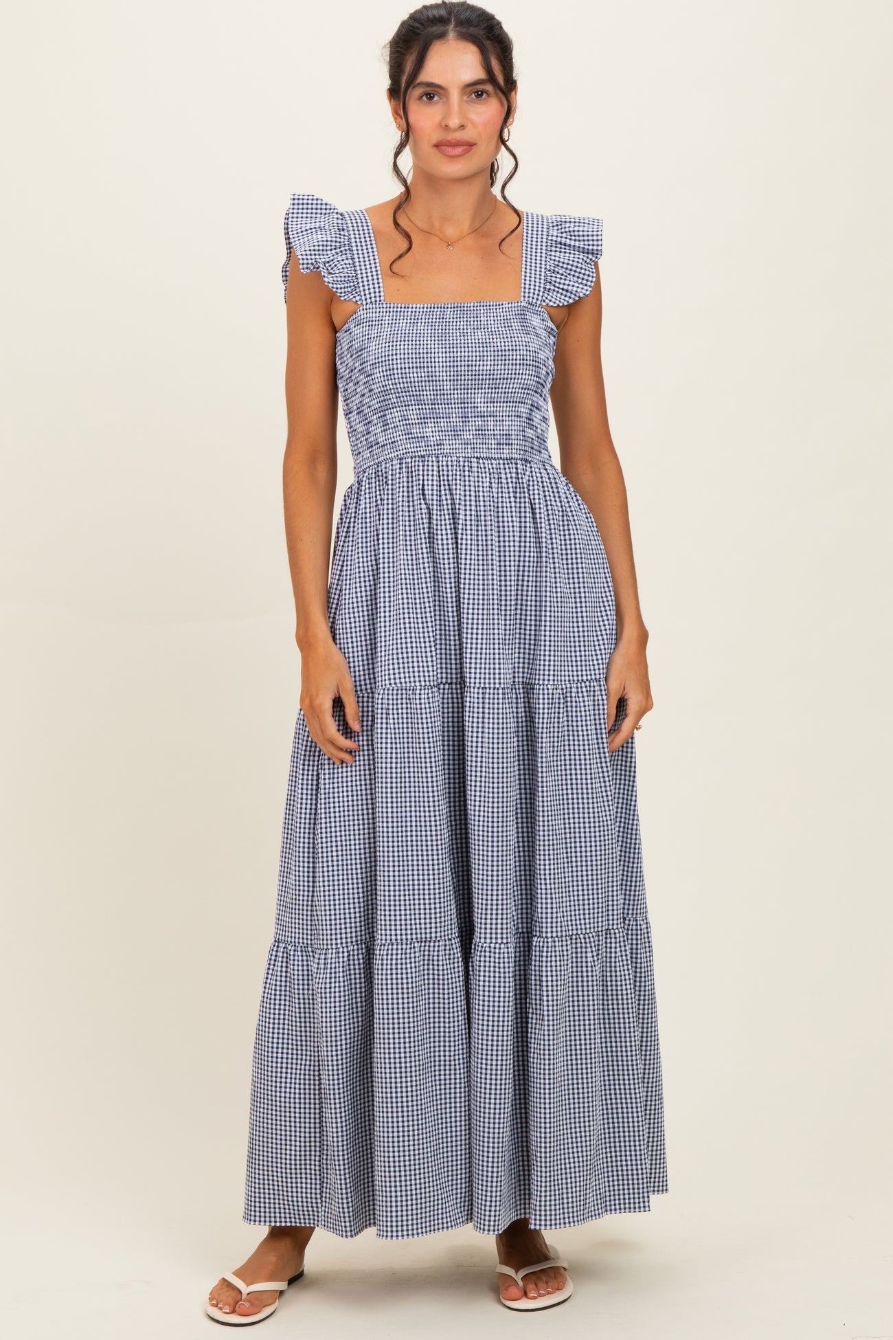 woman wearing a blue and white gingham maxi dress with ruffled shoulder straps and tiered skirt