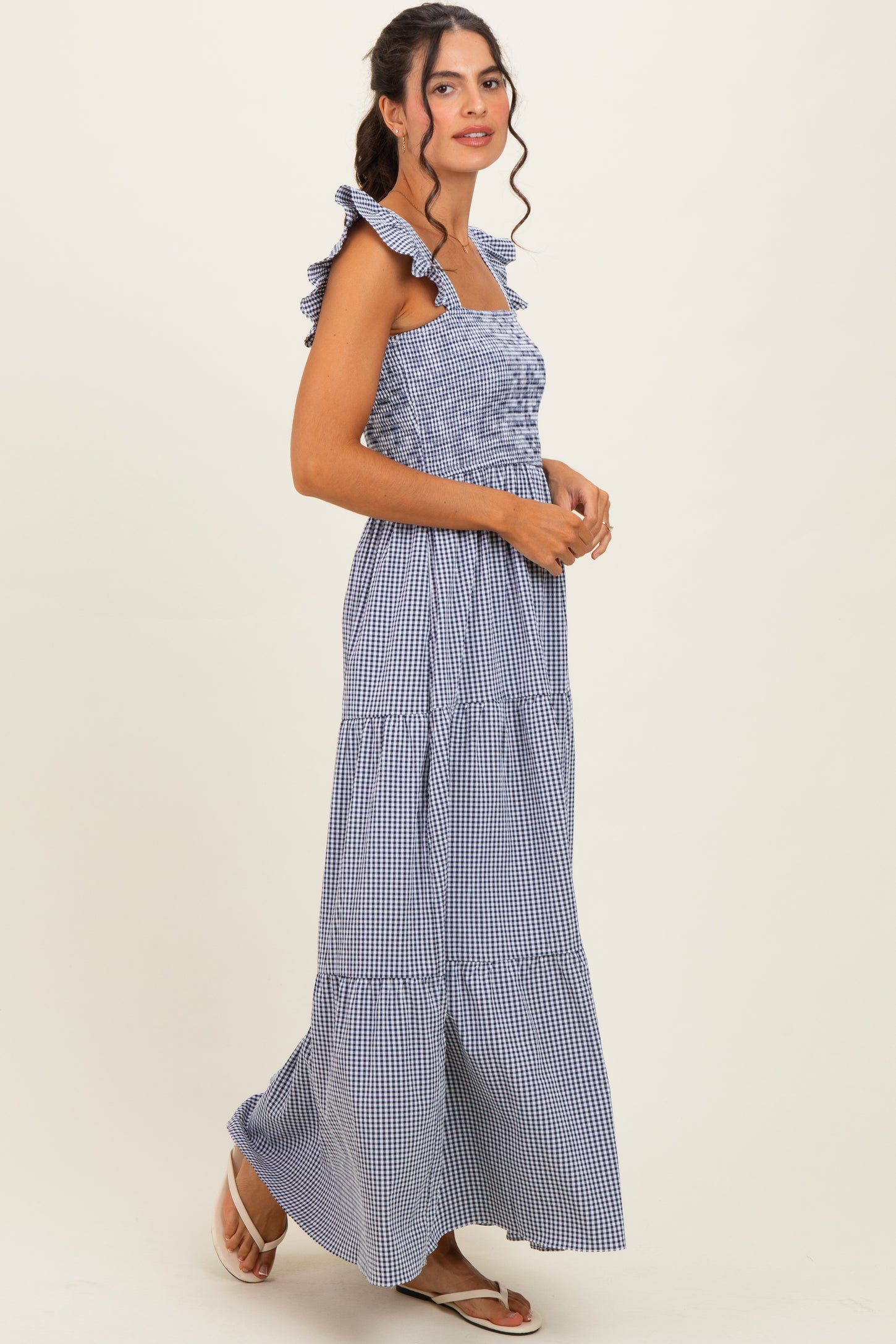 woman wearing a navy and white gingham maxi dress with ruffled straps and tiered skirt