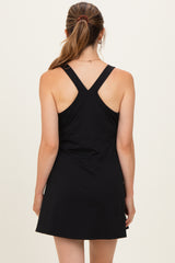 woman wearing a black maternity dress with a racerback style, showing the back view and no visible baby bump