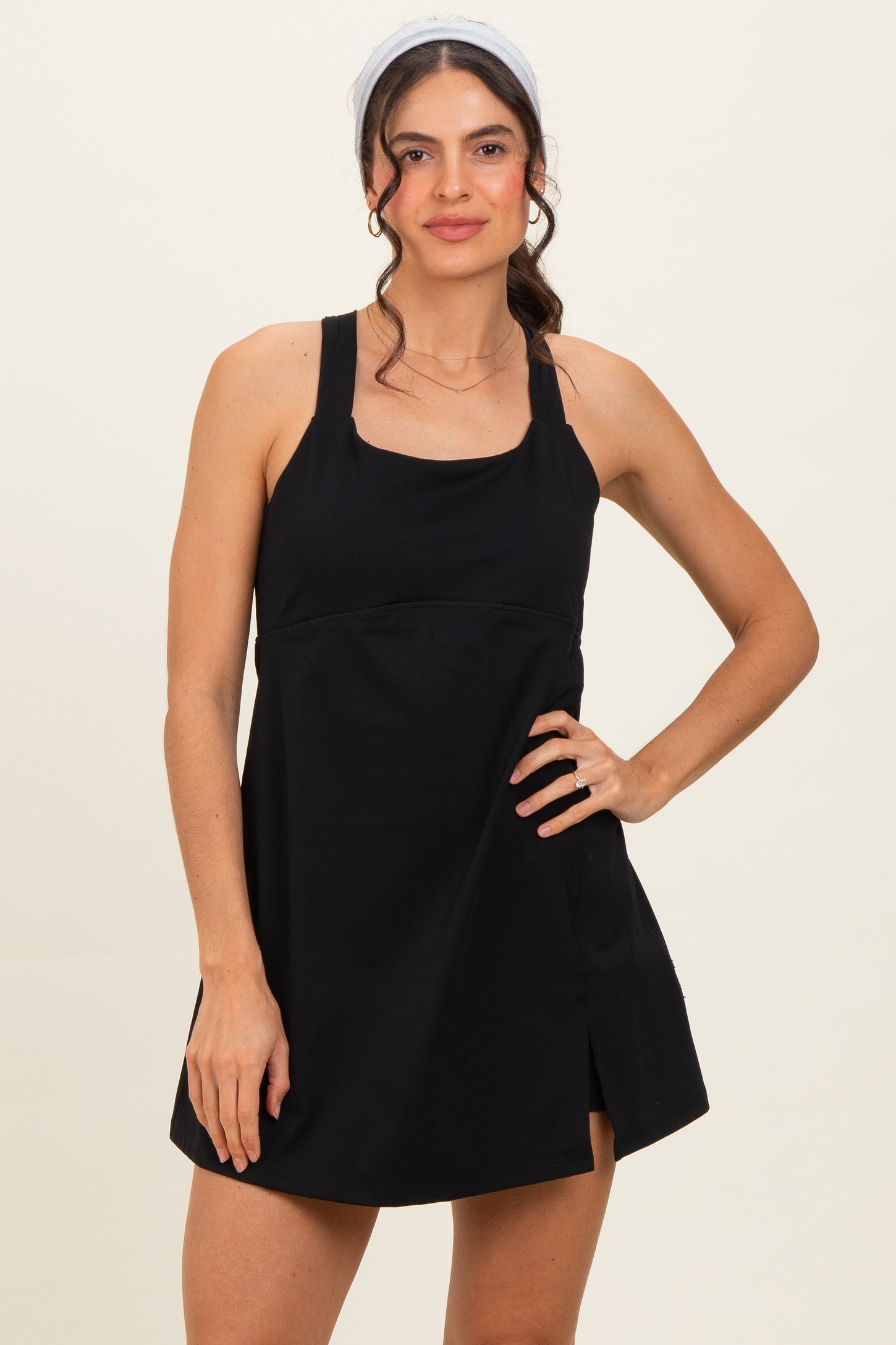 woman wearing a black sleeveless mini dress with a square neckline and side slit, styled with a headband