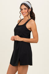 woman wearing a black sleeveless dress with a cinched waist and a side slit, smiling and posing with a headband in her hair