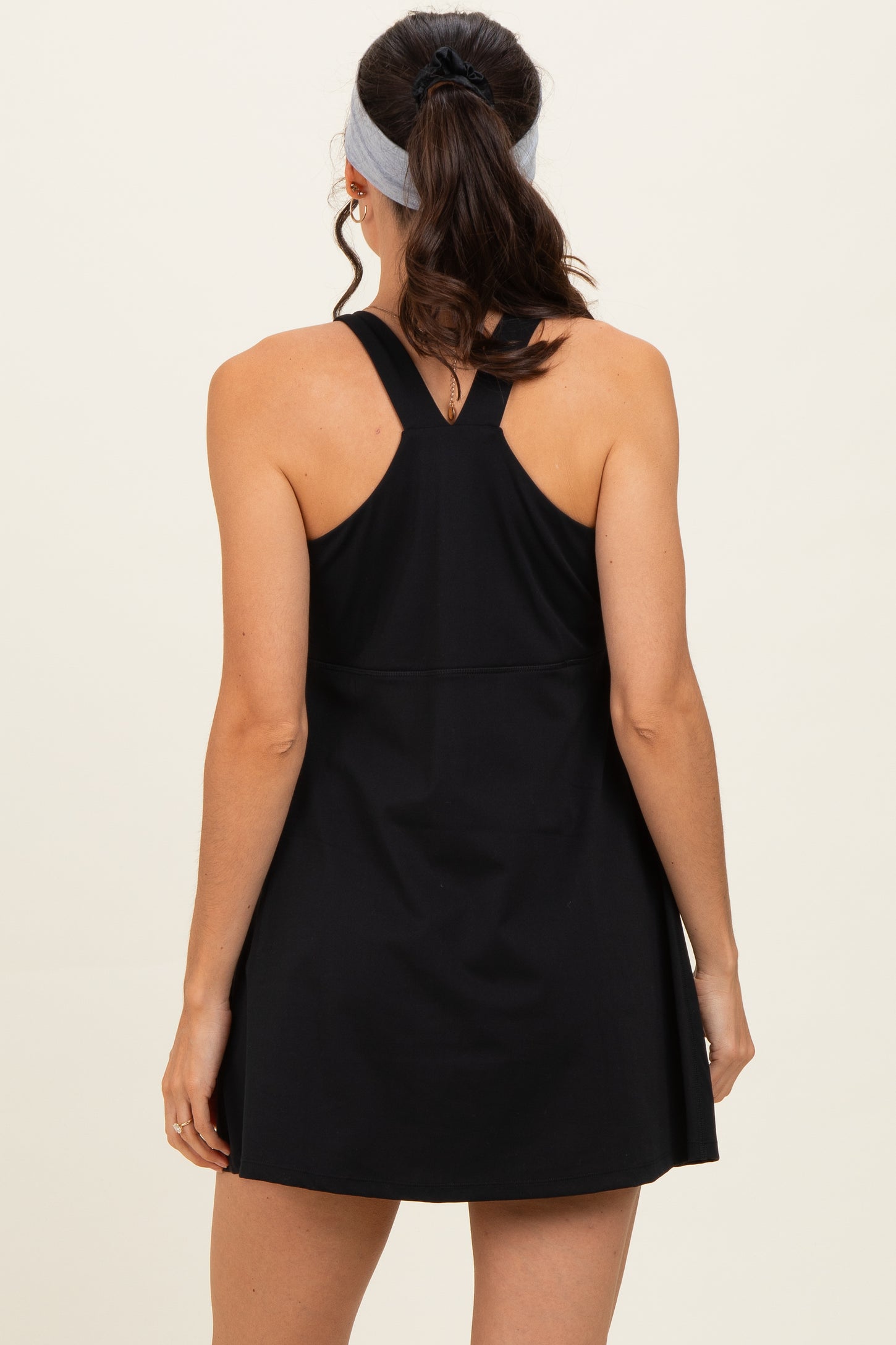 woman wearing a black sleeveless dress with a racerback design, viewed from the back