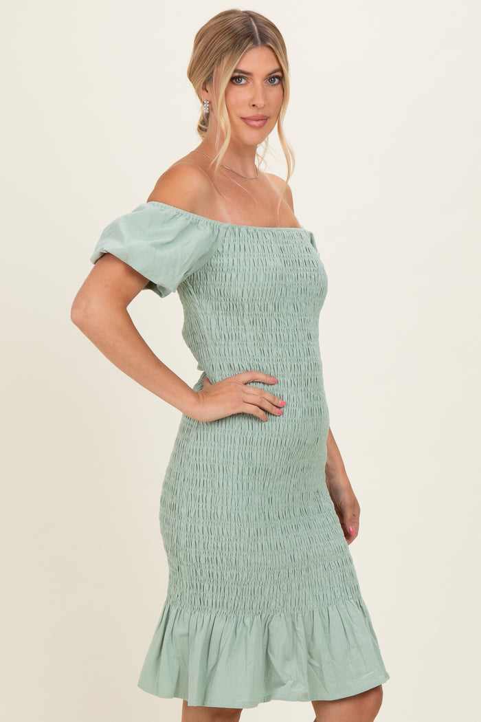 woman wearing a mint green smocked off-the-shoulder dress with short puff sleeves and a flared hem