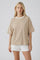 woman wearing a beige oversized t-shirt with short sleeves and white shorts