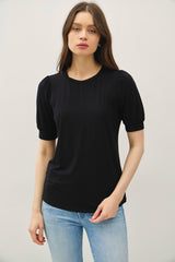 woman wearing a black short sleeve top with puffed sleeves and a relaxed fit, paired with light blue jeans