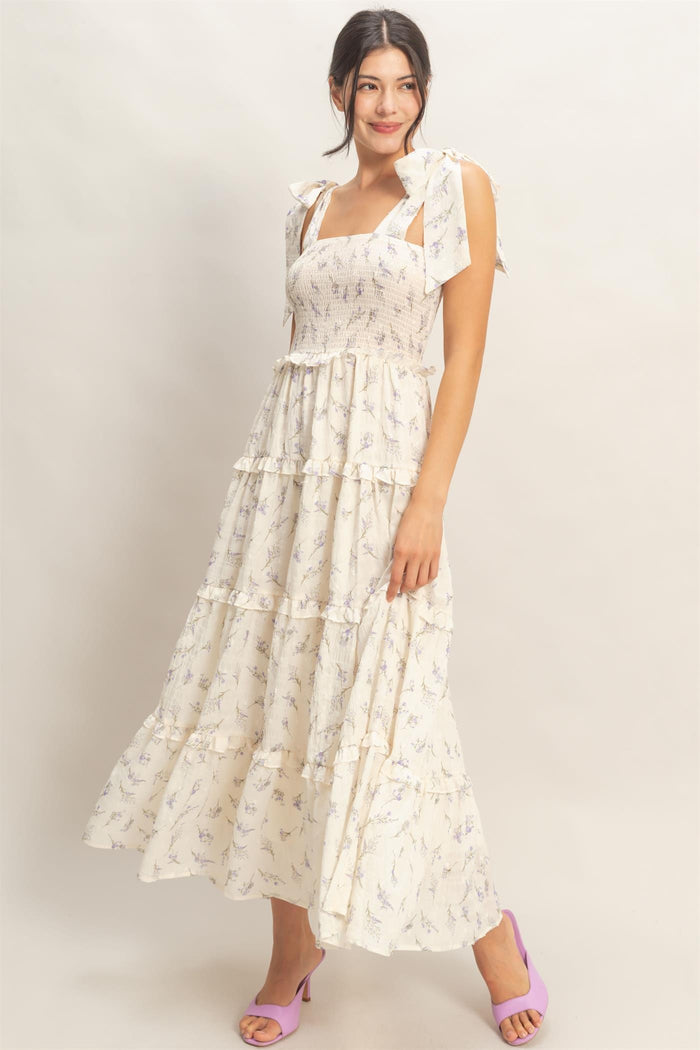 woman wearing a white floral maxi dress with tie shoulder straps and tiered ruffle details