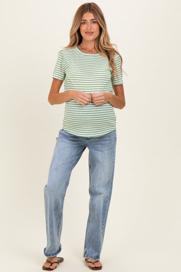 woman wearing a green and white striped maternity top with a round neckline and blue jeans, showing her baby bump
