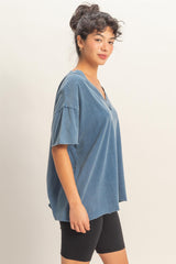 woman wearing a loose-fitting blue v-neck oversized t-shirt with short sleeves and black shorts