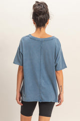 woman wearing a loose-fit blue oversized t-shirt with a raw hem and back seam, paired with black shorts.