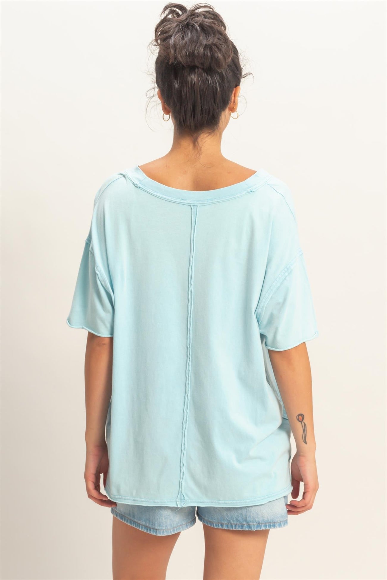 woman wearing a light blue oversized t-shirt with a relaxed fit and short sleeves, styled with denim shorts