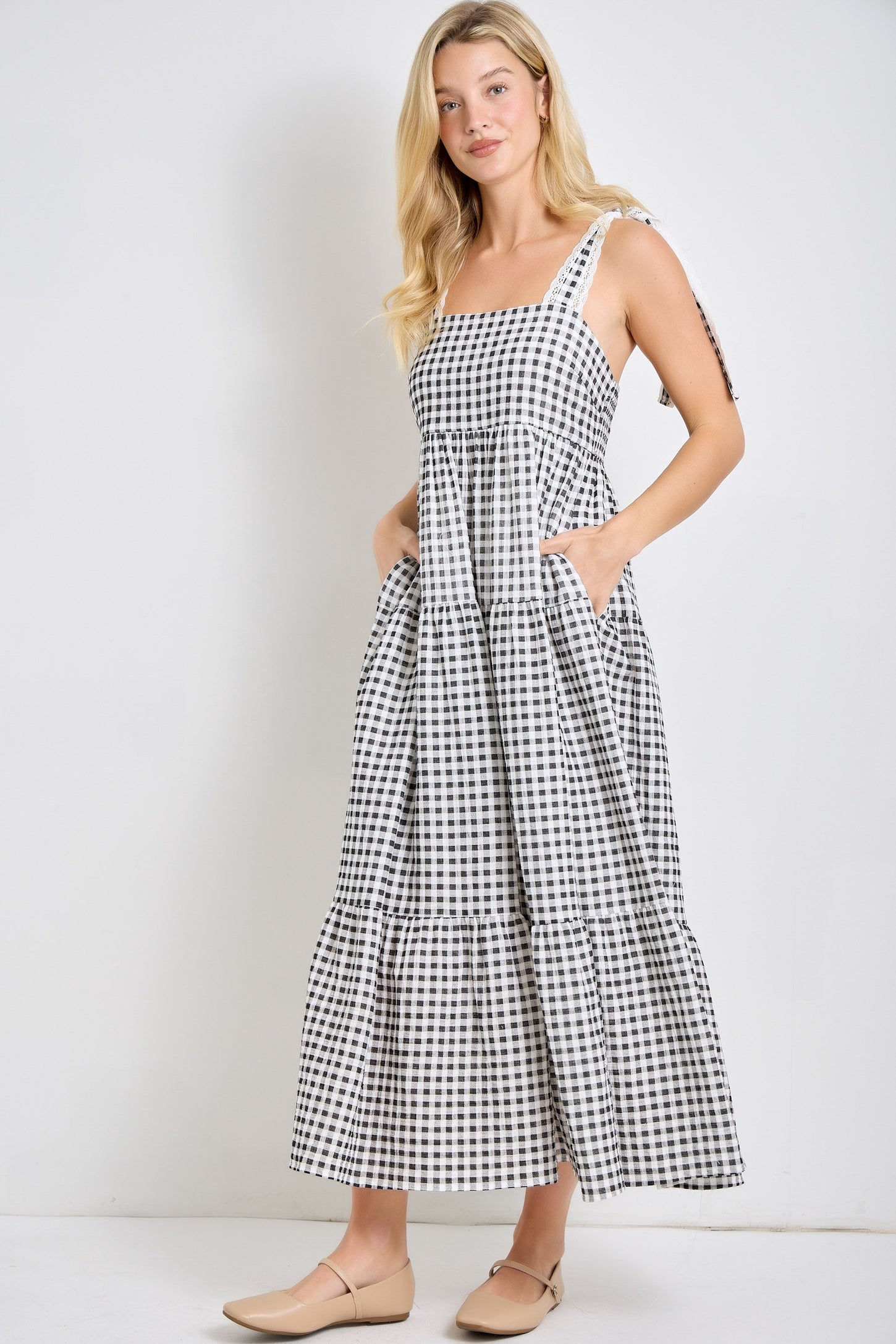 woman wearing a black and white gingham maxi dress with adjustable straps and pockets