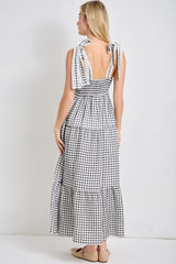 woman wearing a black and white gingham maxi dress with tie straps and a smocked back