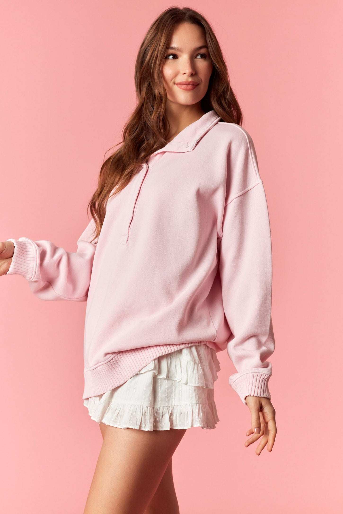 woman wearing a light pink hoodie sweatshirt with a relaxed fit and a white ruffled mini skirt