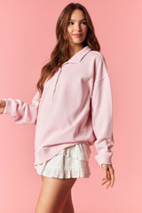 woman wearing a light pink hoodie sweatshirt with a relaxed fit and a white ruffled mini skirt
