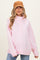 woman wearing a light pink maternity sweatshirt with a high neckline and long sleeves, styled with a tan cap