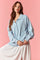 woman wearing a light blue oversized pullover with a collar and front buttons, paired with a white dotted skirt