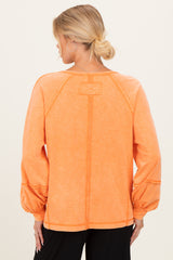 maternity wear in a vibrant orange long sleeve top with puffed sleeves and stitched detailing, view from the back
