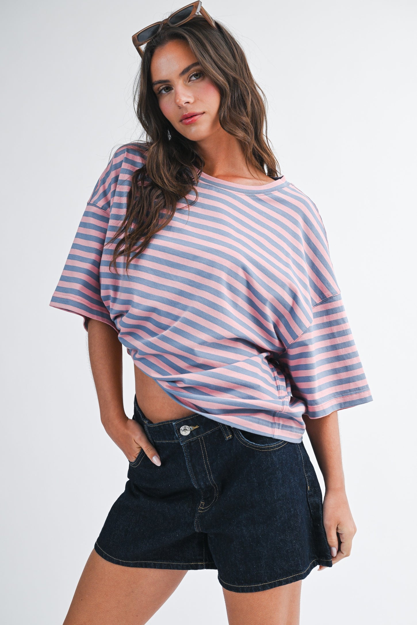 woman wearing a pink and purple striped oversized t-shirt and dark denim shorts