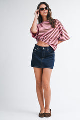 woman wearing a red and white striped oversized t-shirt and a dark blue denim mini skirt, accessorized with sunglasses
