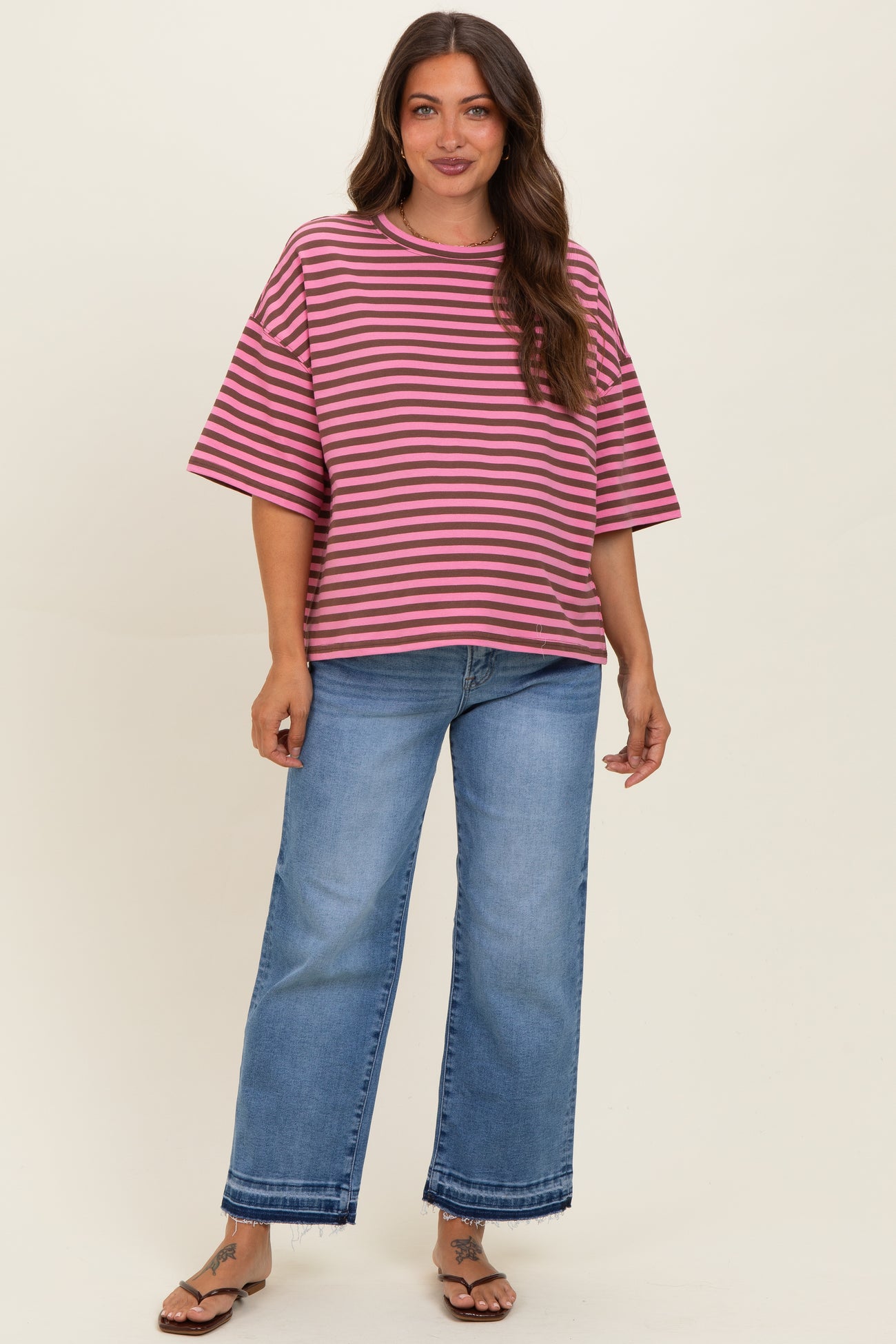 woman wearing a pink and purple striped maternity top with loose sleeves and blue wide-leg jeans
