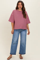 woman wearing a pink and purple striped maternity top with loose sleeves and blue wide-leg jeans