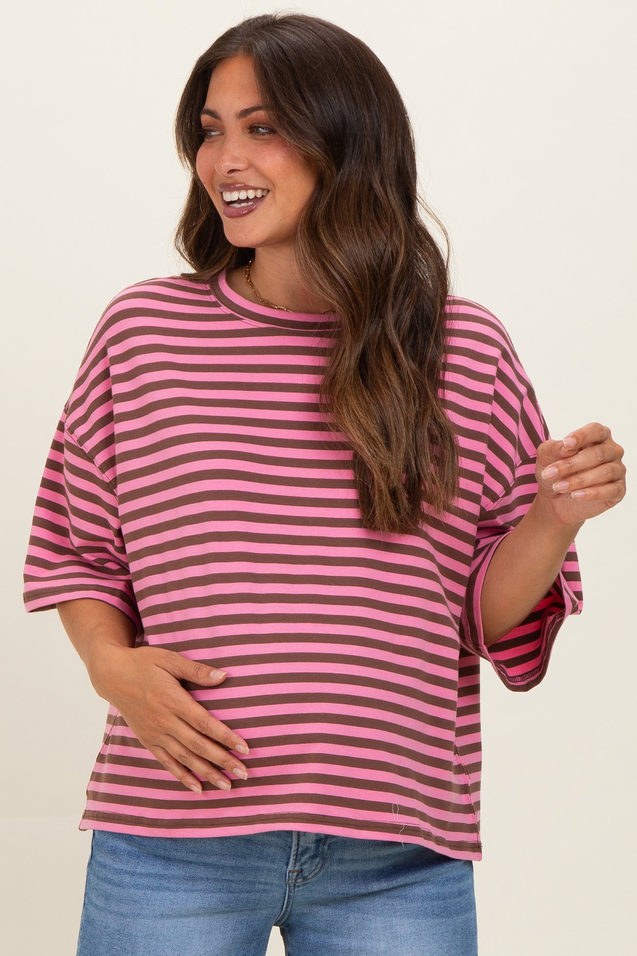 woman wearing a pink and black striped maternity top and holding her baby bump