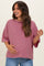 woman wearing a pink and black striped maternity top and holding her baby bump