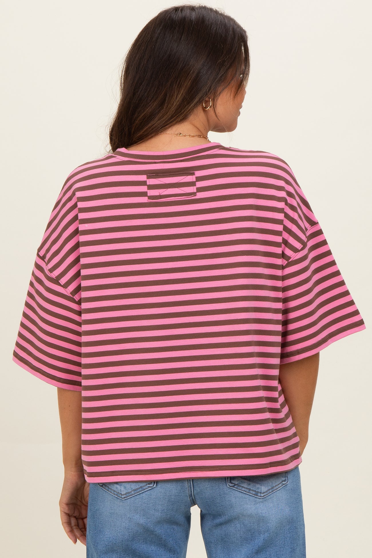 woman wearing a pink and gray striped maternity top with a loose fit and short sleeves, showing the back view